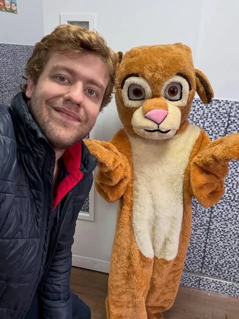 Equipe pedagógica SPORTZ com nosso mascote lúdico acolhendo os alunos em feiras culturais e comunitárias com abraços e alegria compartilhada. 🦁🎒💛